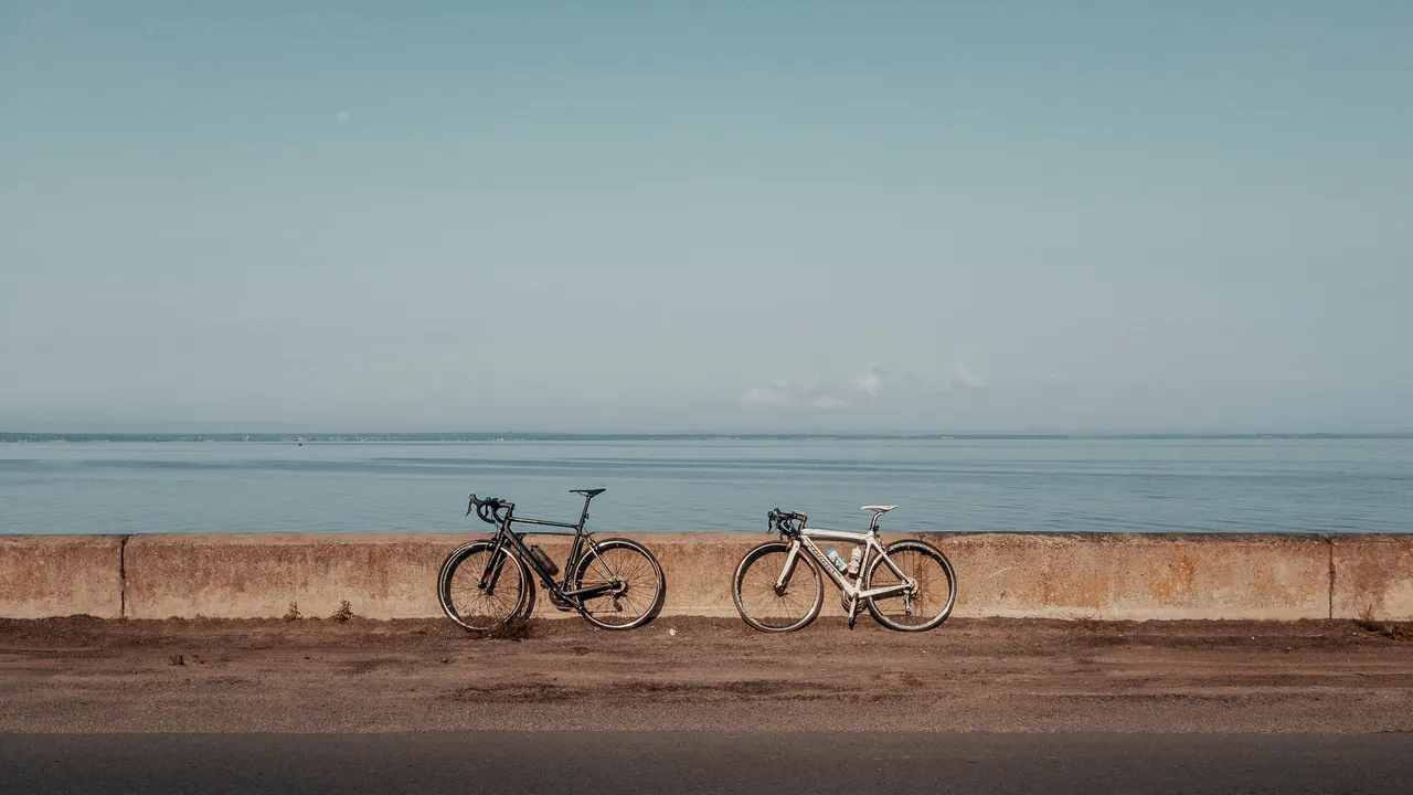 Two road bikes leaning side by side on a sea wall