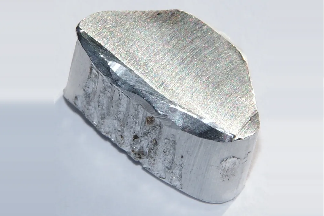 A chunk of shiny, freshly cut aluminium metal on a light background
